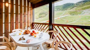A wooden interior with a table set for breakfast, overlooking a mountainous landscape.