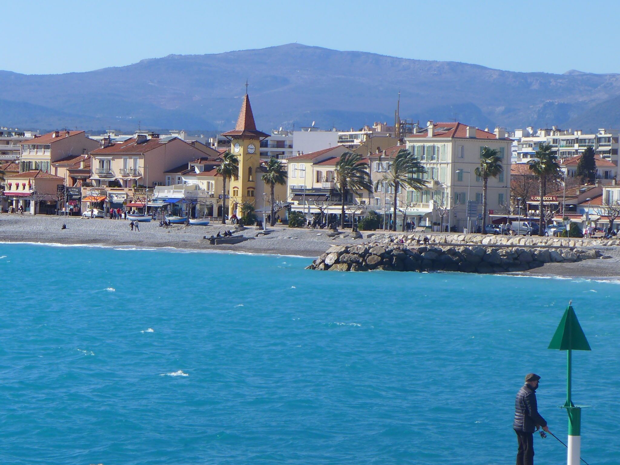 A coastal town with buildings, a beach, and a rocky shoreline.