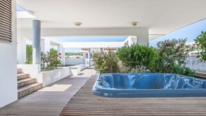 Una terraza en la azotea con jacuzzi, cubierta de madera y plantas en macetas.