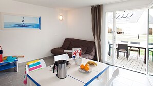 A modern room with a dining table, a sofa, and a view of the outdoors.