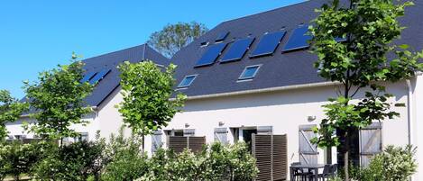 A modern building with multiple skylights, a paved driveway, and well-maintained greenery.