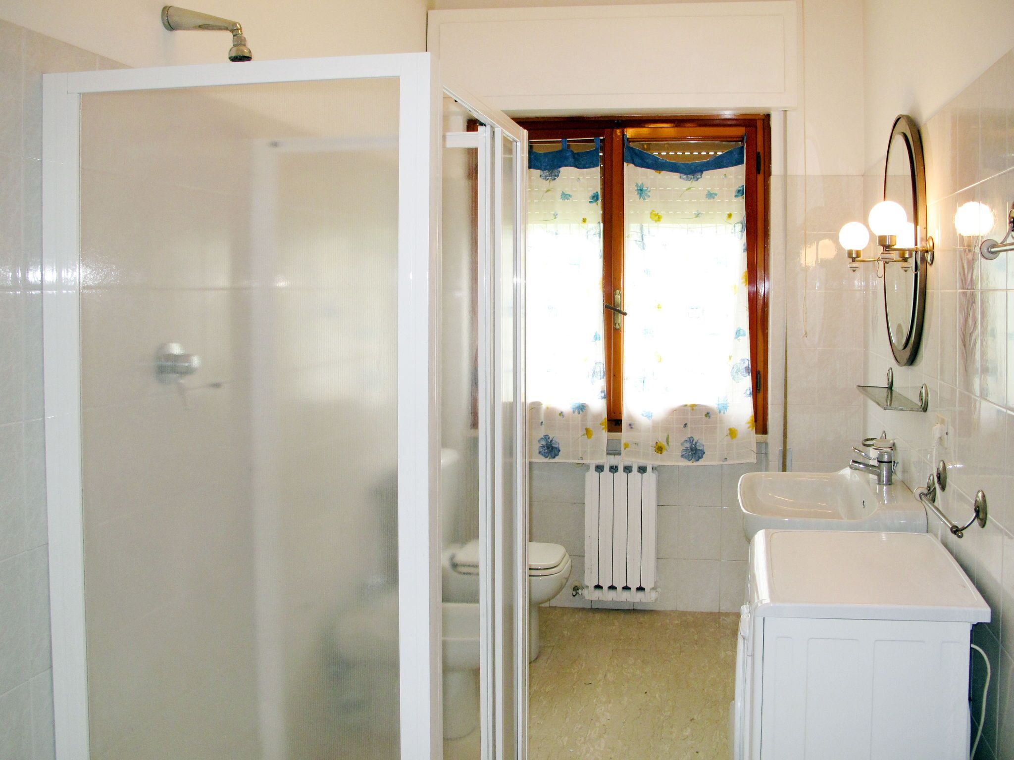 A bathroom with a shower, toilet, sink, and mirror.