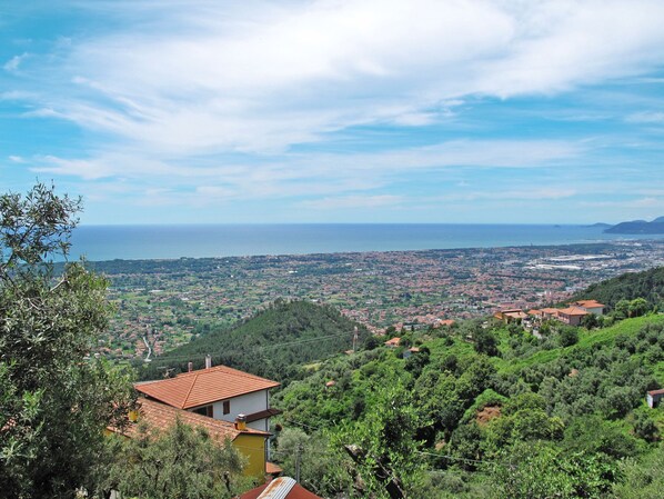 A coastal town with a view of the sea, surrounded by greenery and buildings with red-tiled roofs.