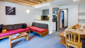 Un espace de vie compact comprenant un canapé, une petite table et une kitchenette.