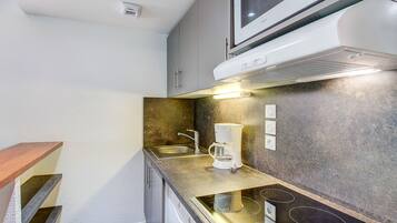 Een koelkast, een magnetron, een vaatwasser, kookgerei, borden en bestek