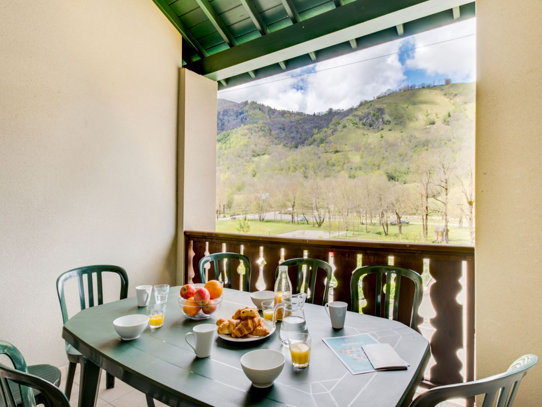 A dining table with breakfast items and a view of a mountainous landscape.