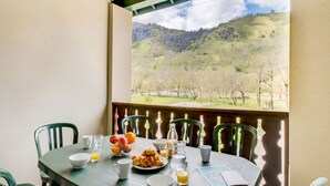 Ein Esstisch mit Frühstücksangeboten und Blick auf eine gebirgige Landschaft.