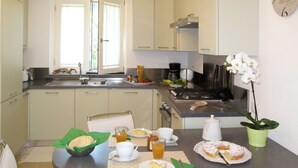 Una cocina moderna con comedor, que incluye un lavamanos, estufa y un reloj en la pared.