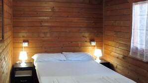 Ein Zimmer in einer Holzhütte mit einem Bett, zwei Nachttischen und zwei Lampen.