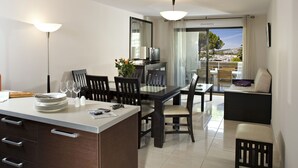 A modern dining area with a central island, black chairs, and a sofa with cushions.