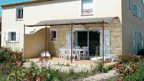 Ein zweistöckiges Gebäude mit einer Terrasse, die Gartenmöbel bietet.