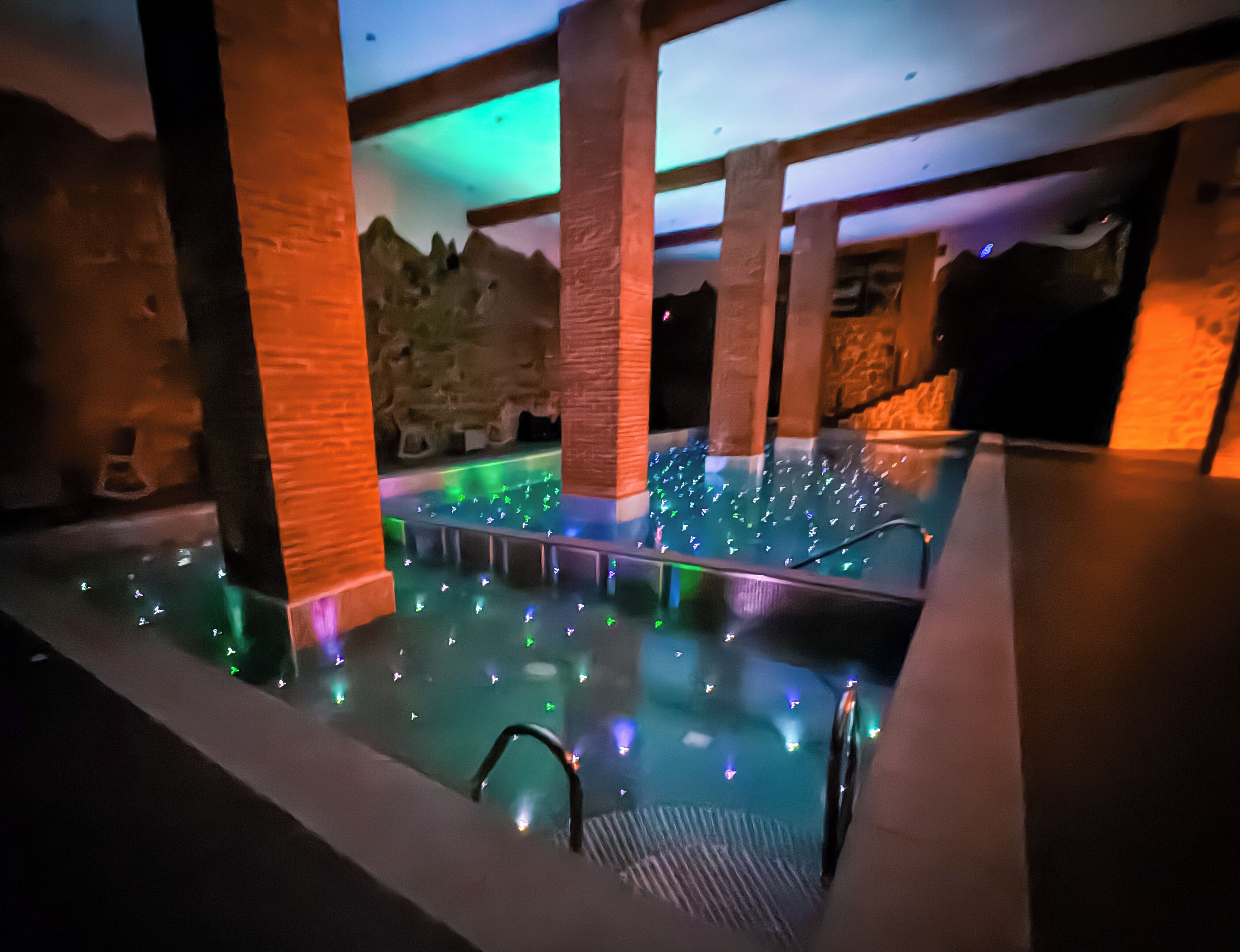 An indoor pool with a stone wall backdrop and illuminated water features.