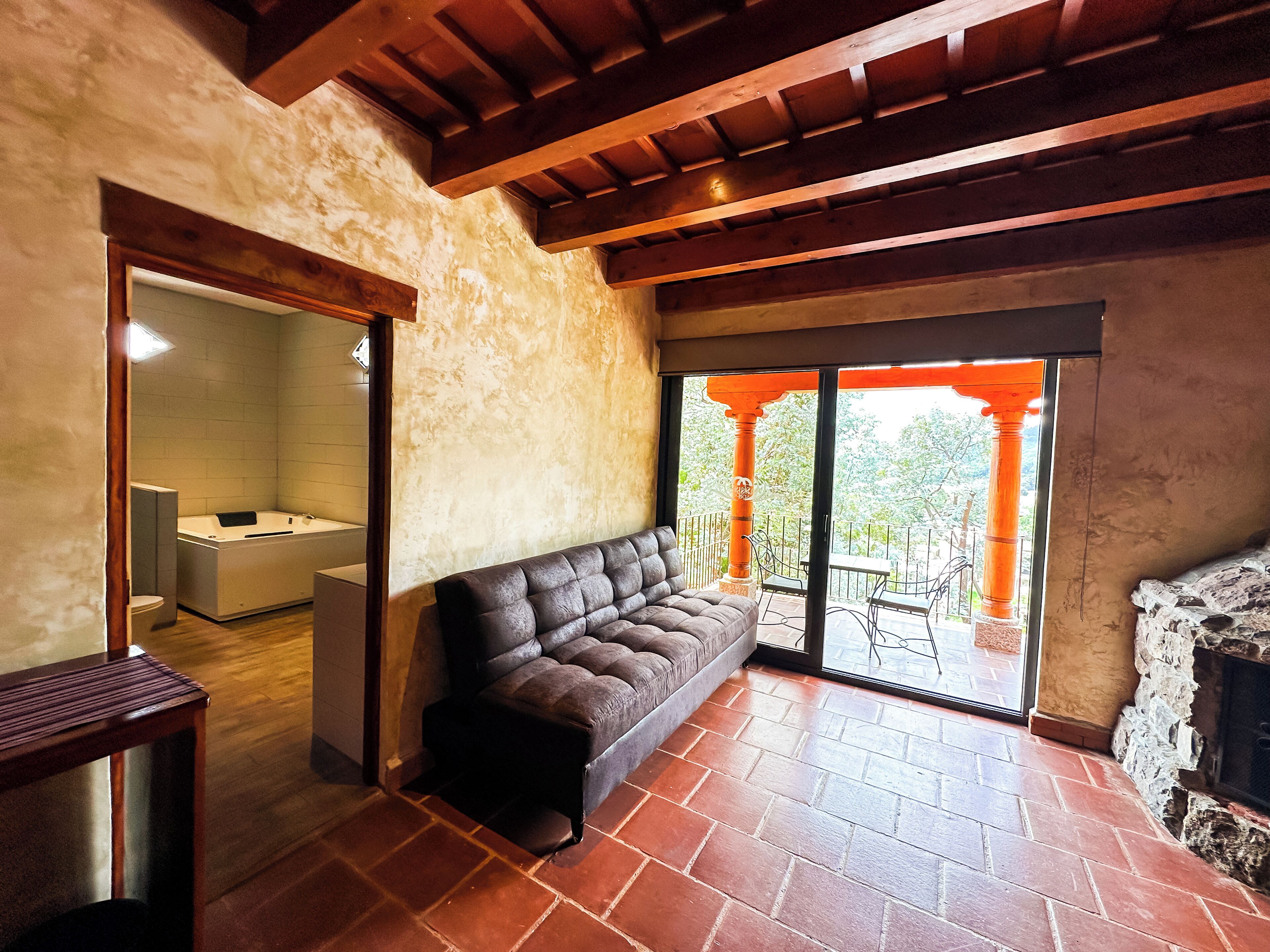 A spacious living area with a large sofa, a fireplace, and a view of the outdoors.