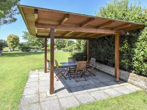 Eine Holzpergola mit Tisch und Stühlen in einem Garten.