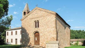 A stone church with a bell tower and a white building with shutters.