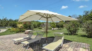 A patio area with lounge chairs and a large umbrella.
