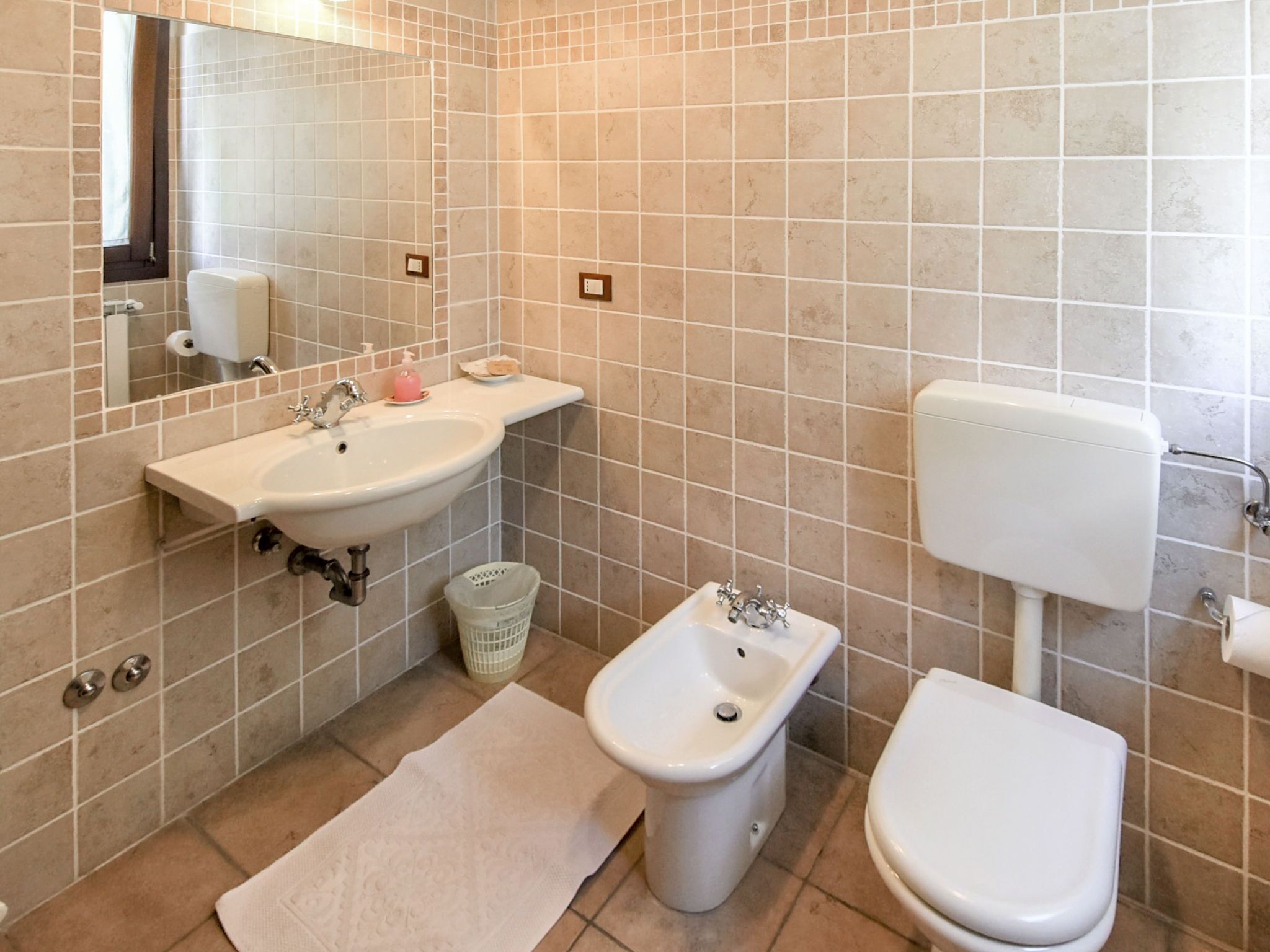 A bathroom with a sink, bidet, toilet, and a mirror.