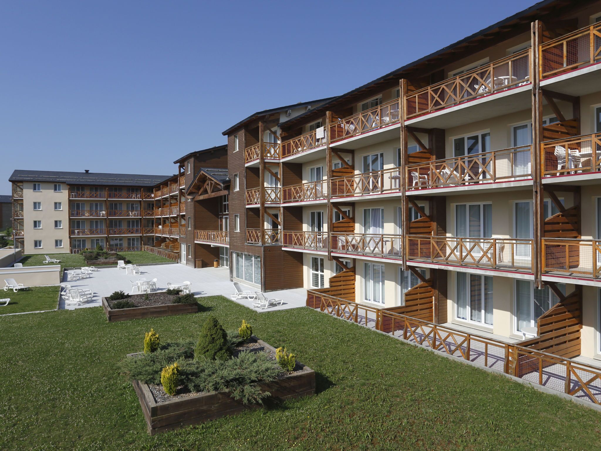 Een hotel met meerdere verdiepingen, houten balkons en een aangelegde binnentuin.