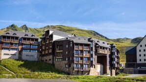 Un hotel a più piani con balconi e uno sfondo montuoso.