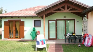 A small house with a tiled roof, a patio with a table and chairs, and a green inflatable pool. - Rosolina Mare Club by Interhome (Rosolina Mare)