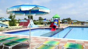 Un espace piscine comprenant des chaises longues et un toboggan.