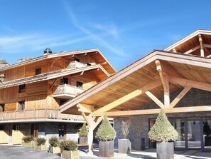 A wooden multi-story building with balconies and a covered entrance area.