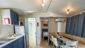 Une chambre d’hôtel compacte comprenant un coin cuisine, un espace repas avec une table et des chaises, une douche et un lit.