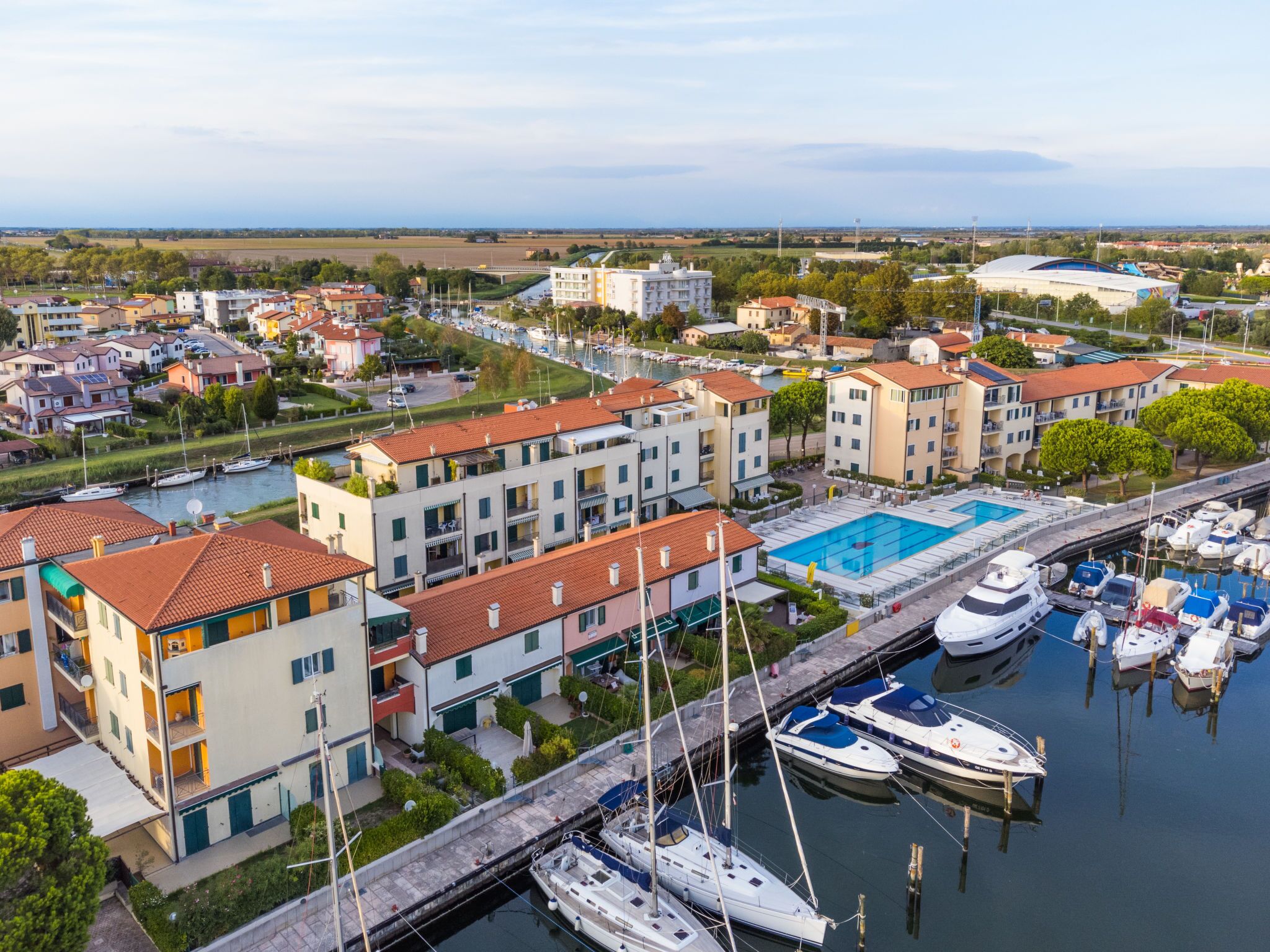 A marina with boats docked, a swimming pool, and residential buildings with balconies.