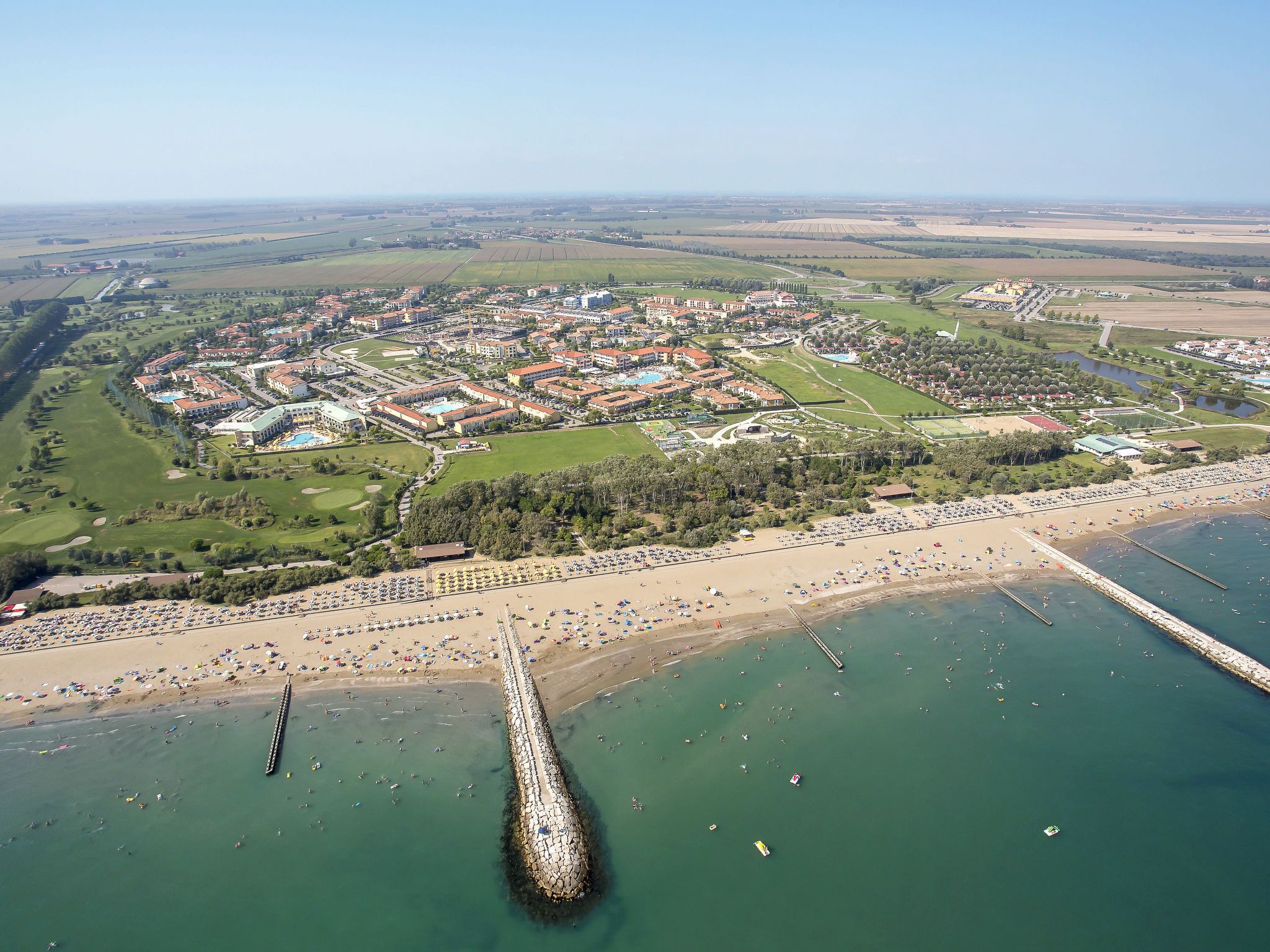 An aerial view of a coastal resort with a marina, beach, and golf course.