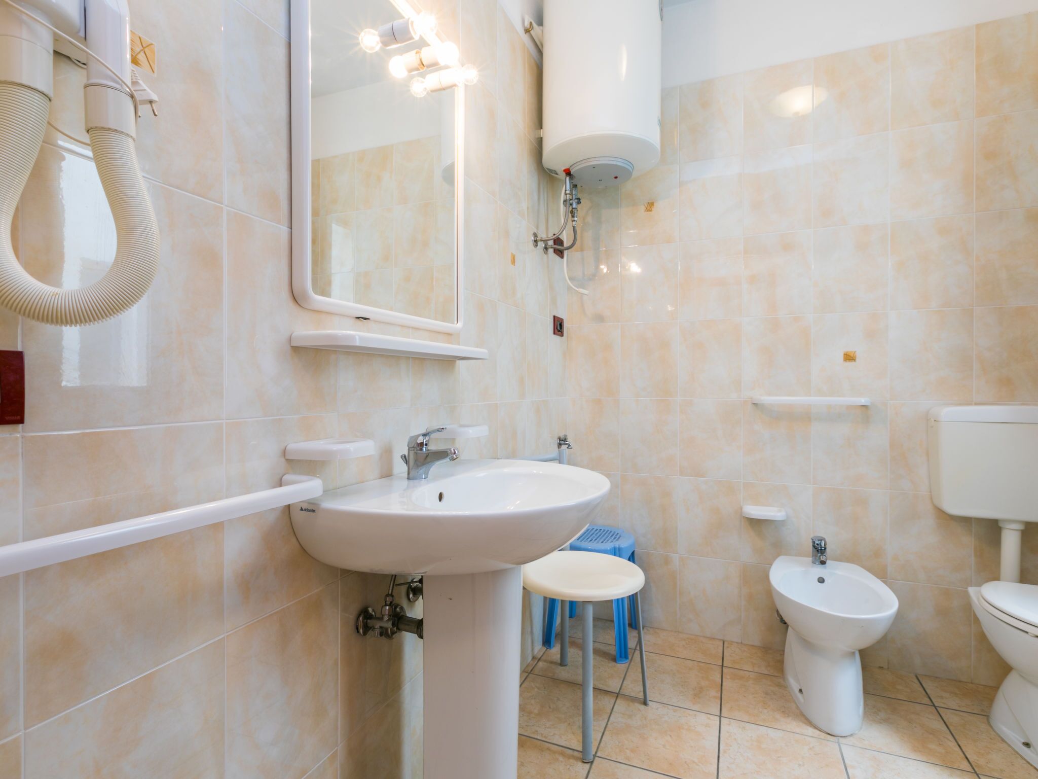 A bathroom with a sink, mirror, bidet, toilet, and towel rack.