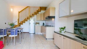 A modern kitchen with wooden cabinets, a stainless steel refrigerator, and a built-in oven. - Robinia/Pinetine by Interhome (Caorle)