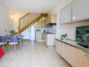 Een koelkast, kookgerei, borden en bestek, eettafels