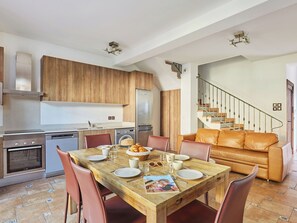 A modern kitchen with wooden cabinets, stainless steel appliances, and a dining area with a wooden table and leather chairs. - Villas Odalys Collection Orée de Milady by Interhome (Biarritz)