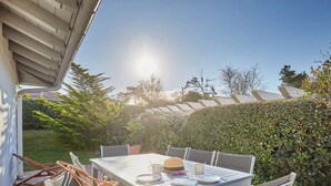 Un patio al aire libre con una mesa dispuesta para dos, rodeada de sillas, una cesta tejida y un par de gafas de sol.