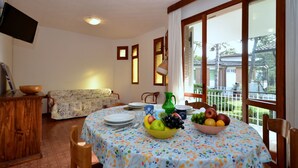 Un comedor con una mesa preparada para dos personas, un sofá y un televisor montado en la pared.