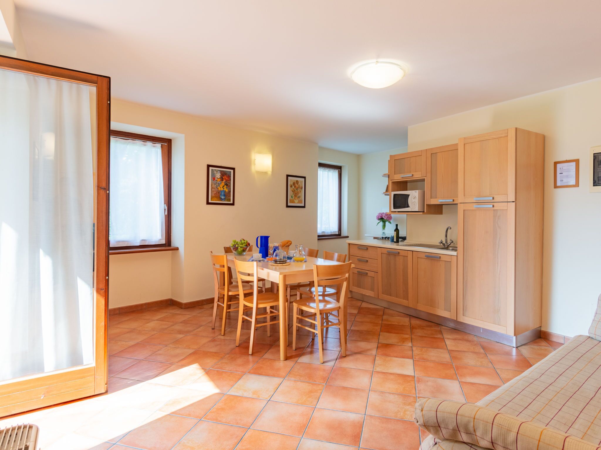 A compact kitchen with wooden cabinets, a dining table with chairs, and a tiled floor.
