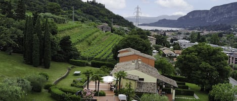 A pool area with lounge chairs and umbrellas, surrounded by well-maintained gardens and a view of a mountainous landscape.