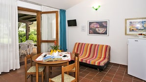 A cozy room with a dining table, chairs, a sofa, a TV, and artwork on the walls.