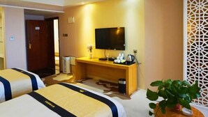 A hotel room with two beds, a TV, a desk with a coffee maker, and a plant. - Green Journey Inn (Suzhou)
