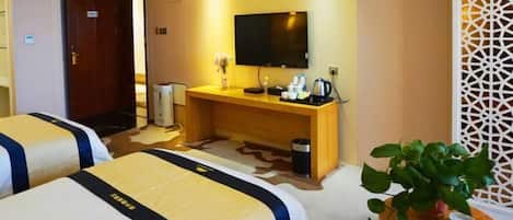 A hotel room with two beds, a TV, a desk with a coffee maker, and a plant.