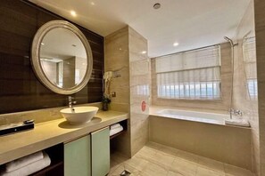 A modern bathroom with a round mirror, a sink, a bathtub, and a window with blinds. - Green Journey Inn (Suzhou)