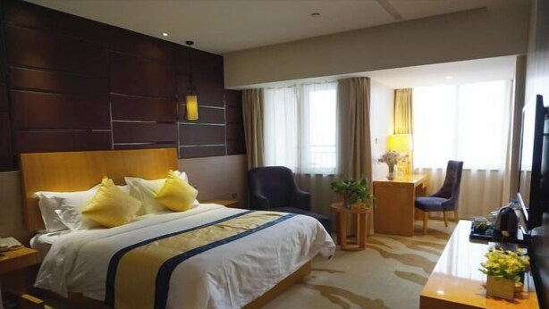 A hotel room with a bed, a desk, a chair, a TV, and a window with curtains. - Green Journey Inn (Suzhou)