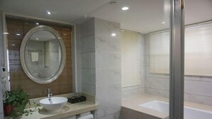 A modern bathroom with a round mirror, a white sink, a bathtub, and a potted plant. - Green Journey Inn (Suzhou)