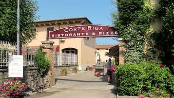 Ein Restaurant Eingang mit einem Schild, auf dem 'Corte Riga Ristorante & Pizza' steht.