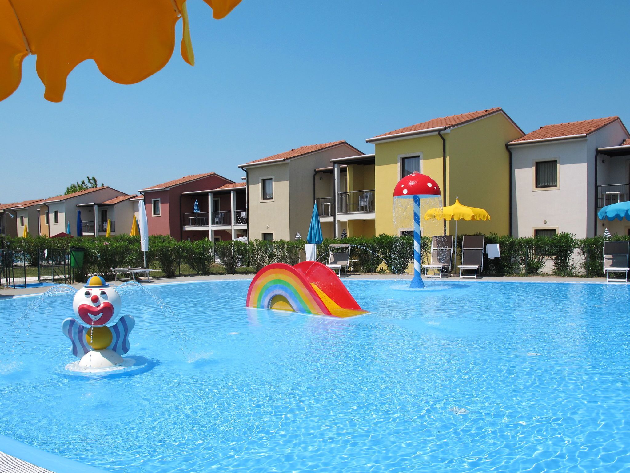 A swimming pool with colorful water features and adjacent hotel buildings.