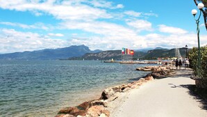 Ein Küstenweg mit freiem Blick auf das Meer, einer felsigen Küstenlinie und entfernten Bergen.