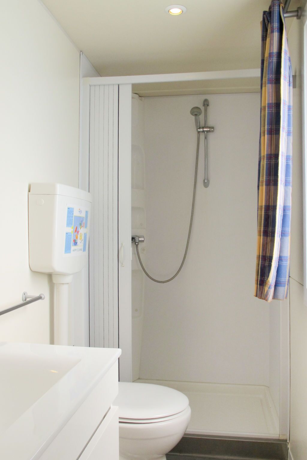 A small bathroom with a toilet, a shower, and a white sink.