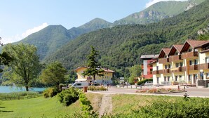 Un hôtel doté de nombreux balcons, offrant une vue sur un lac et s’inscrivant dans un paysage montagneux.