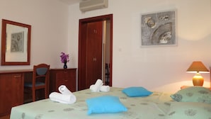 Une chambre d’hôtel comprenant un lit, un bureau, une chaise, une armoire, un climatiseur fixé au mur et un tableau.