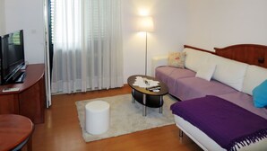 Une chambre d’hôtel de taille réduite, comprenant un lit, un canapé, une petite table, un téléviseur et une lampe.